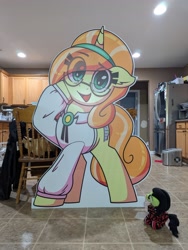 Size: 3072x4080 | Tagged: safe, artist:zajice, oc, oc:adventurefilly, oc:filly anon, oc:fun raiser, clothes, earth pony, female, filly, foal, glasses, horn, imported from derpibooru, indoors, irl, kitchen, looking at you, mare fair, oc only, open mouth, open smile, photo, plushie, pony, refrigerator, shirt, smiling, unicorn