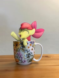 Size: 3024x4032 | Tagged: safe, artist:funnygrin, apple bloom, cup, derpibooru exclusive, earth pony, eyes closed, female, filly, foal, g4, imported from derpibooru, indoors, irl, open mouth, open smile, photo, photoshop, ponies in real life, pony, smiling, solo